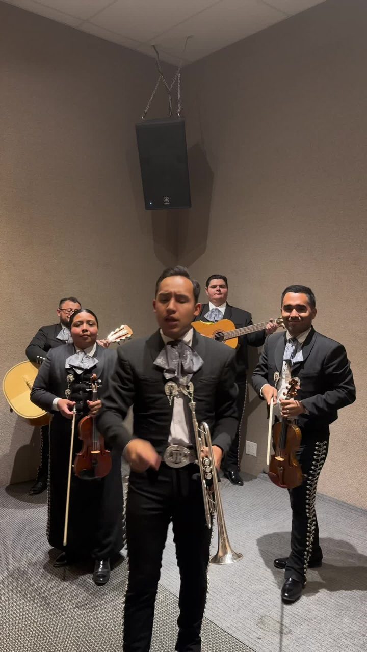 The full ensemble performing indoors with trumpet, violins and guitar